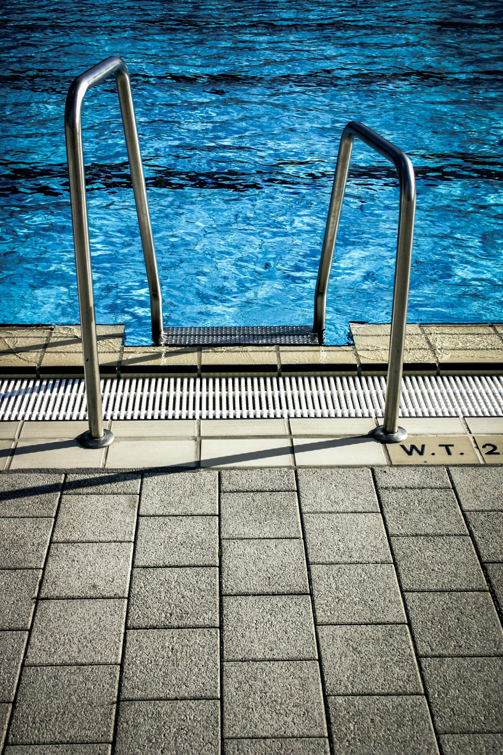 Close-up of a pool ladder with blue water, showcasing a serene outdoor setting.